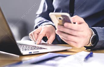 Multitasking and mobile technology. Busy workaholic business man using phone and laptop. Entrepreneur working hard with smartphone