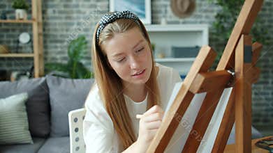 Slow motion of happy girl painting at home alone using easel, paper and pencils