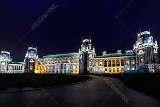Night panorama of the magnificent old Gothic castle illuminated by yellow lights against the dark blue sky