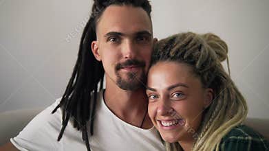 Close up portrait of the young dreadlock couple in love looking directly to the camera and smiling on the white