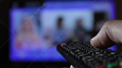 Close-up of a remote control held by a man while changing channels compulsively