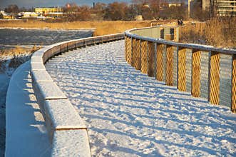Wooden boardwalk to the mole of Pärnu covered by fresh snow in winter morning