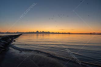 Sunset over mole of Pärnu coloring water of Baltic sea in orange, blue and yellow