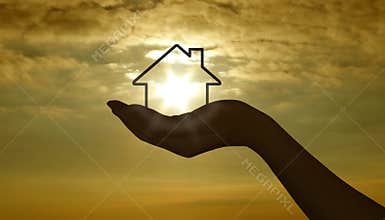 Hand with house at sunset