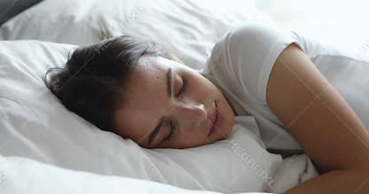 Happy calm millennial woman sleeping in comfortable bed.