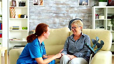 Female nurse holding old woman hand in nursing home