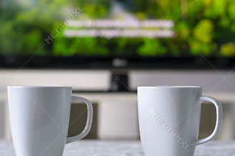 Coffee mugs with a television with a nature documentary and subtitles in background