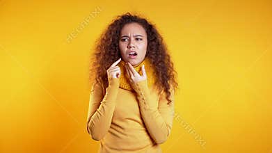Young pretty woman with tooth pain on yellow studio background. Toothache