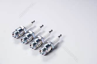 Subject shooting on a gray background. new four spark plugs, spare parts for a gasoline engine. The concept of new auto