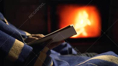 Man with beard is drinking hot tea near fireplace in winter night