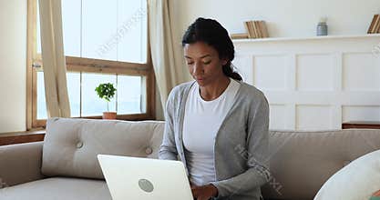 Focused young african ethnicity woman typing message on computer.