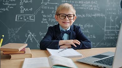 Slow motion of prodigy kid in university classroom at desk with chalkboard in background