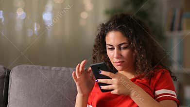 Serious arab girl checking smart phone at home