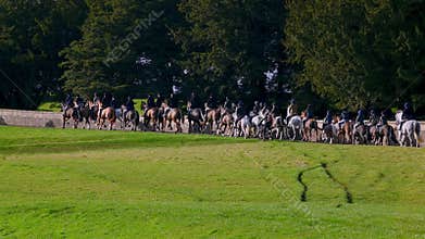 Horse riding fox hunters set off through Capability Brown designed parkland at the beginning of a fox hunt