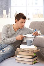University student writing notes at home