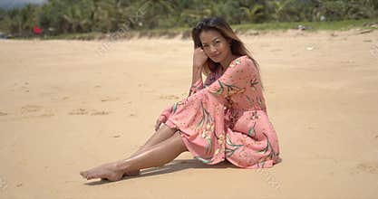 Barefoot ethnic woman sitting on beach
