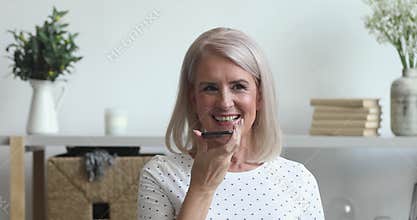 Smiling senior woman activate virtual digital voice assistant on phone