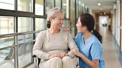 Friendly employee of nursing home talking to senior resident in hallway