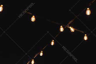 Light bulb decor in outdoor party. Decorative outdoor string lights at night time. Golden glowing garlandon in wedding