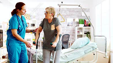 Social worker or nurse helping an elderly woman to walk with crutches