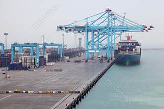 Men load cargo boat docked to industrial port