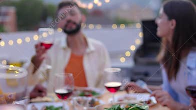 Group of young people toasting red wine at rooftop party