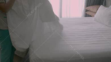 Womans changing the bedding in the room. Employees, two maids of the hotel, professionally make the bed in the