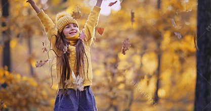 Autumn forest and playing girl with yellow falling leaves, happy freedom childhood