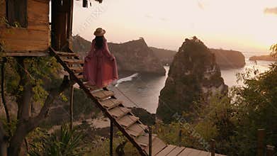 4K video of woman pink dress stand of tree house. Nusa penida, Bali, indonesia.