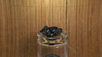 Shungite on a jar against a brown raffia background
