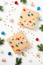 DIY handmade by kids Christmas gift boxes with colorful balls, garland, fir branches on white background
