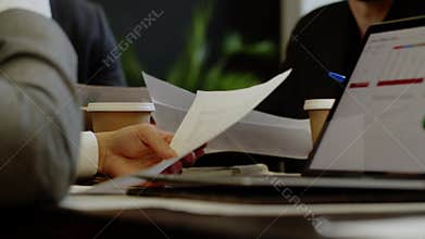 Closeup shot of businessman reading documents actual information about market situation. Colleagues review diagram