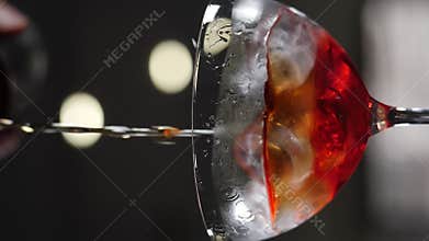 Bartender pouring liquid out of bottle to make cocktail closeup. Vertical footage. Slow motion. Refreshing iced beverage