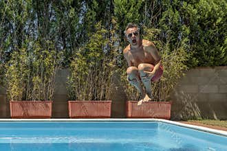 Middle-aged white man dives into the pool with swimming goggles, cannonball style