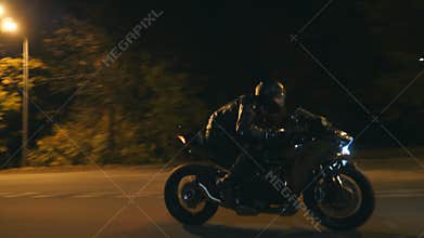 Young man in helmet riding fast on modern sport motorbike at evening city street. Motorcyclist racing his motorcycle on
