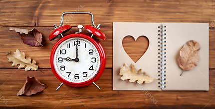 Alarm clock with autumn leaves and book, daylight savings time, fall banner