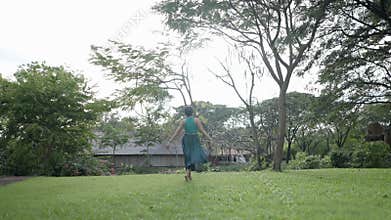 Carefree Woman On The Garden Meadows At The Park Of Ancient City In Bangkok, Thailand. Wide Shot