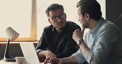 Businessmen discuss ideas sit at desk look at laptop screen