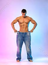 The man demonstrates problems with potency. Size matters. Young man showing how much weight he lost with big jeans. Fat