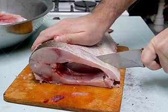 Man prepares fresh silver carp fish. Cuts it into steaks with a knife. home cooking concept