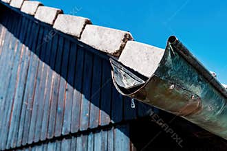 Old worn house rain gutter with water drop