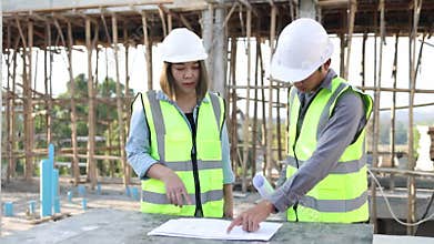 Civil engineer and construction worker manager holding digital tablet and blueprints , talking and planing about construction site
