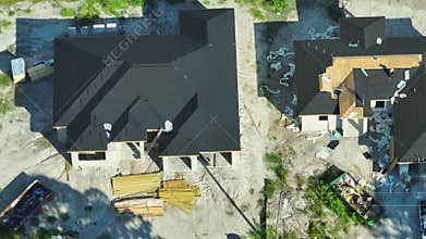 Aerial view of workers working on residential private home covering wooden roof with asphalt shingles. House under