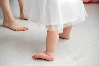 Little girl is learning to walk. Baby's first birthday. elegant baby