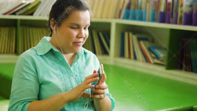 Portrait of Asian woman with blindness disability wearing earphones enjoy using smart phone with voice accessibility for persons