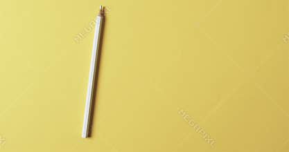 Overhead view of white crayon with copy space on yellow background, in slow motion