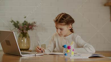 A quick-witted girl sits at her desk and is engaged in a writing lesson. Children and other learning with the help of