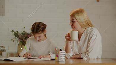 Mom drinks her coffee and controls how her preteen daughter does her homework. The concept of help and praise from
