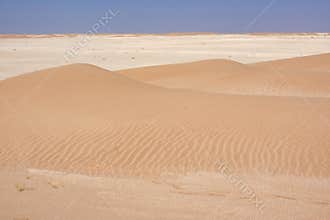 Small cross desert dunes golden on the horizon limestone expanse. Oman