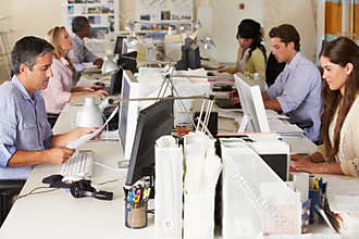 Team Working At Desks In Busy Office